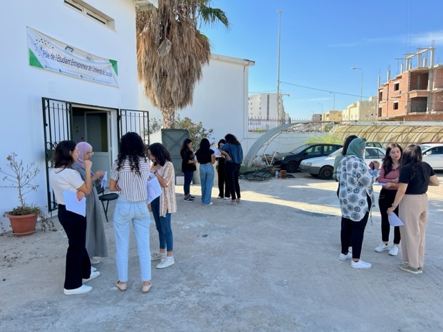 Drei kleine Grüppchen von Studierenden stehen draußen vor einem Gebäude in Tunesien