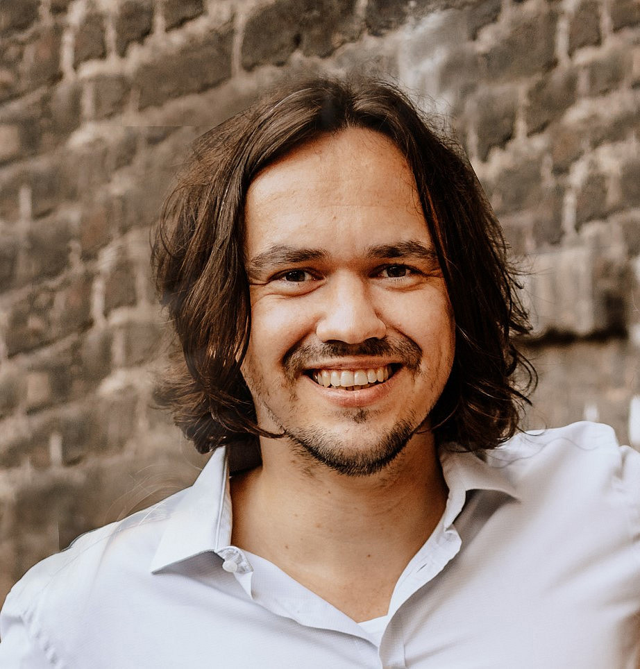 Portraitaufnahme eines lächelendes Mannes vor Backsteinwand