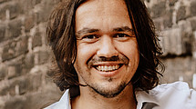 Portrait of a smiling man in front of a brick wall