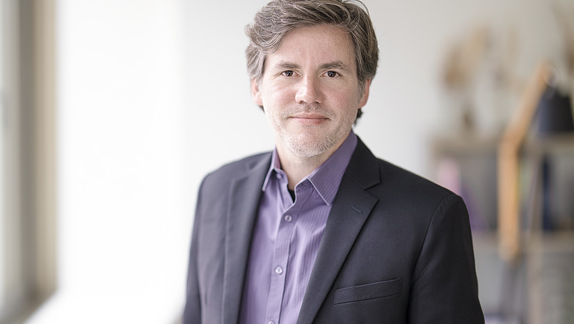 Portraitfoto von Jens Behrmann, wie er leicht lächelnd in die Kamera blickt.