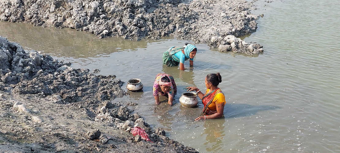 Women stand in the water.