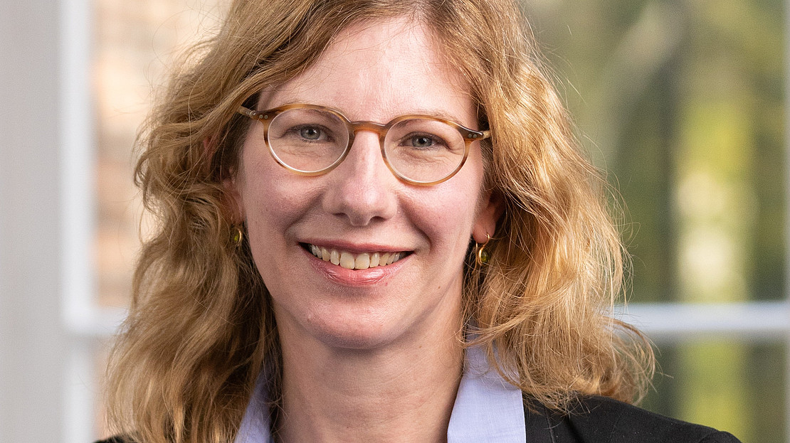 Portraitfoto von Bärbel Wesselborg. Lächelnd, blonde Locken, Brille, Bluse und Blazer 