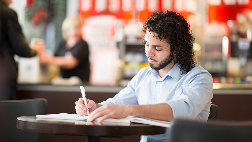 Schreibender Student in einem Café