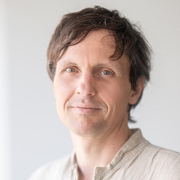 Man with a beige shirt and a friendly smile