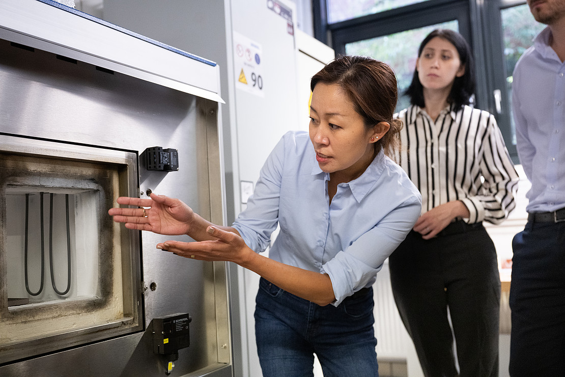 Wenwen Song zeigt auf großes technisches Gerät