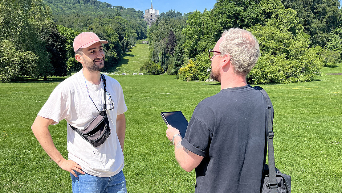 Zwei Männer, Befragung im Bergpark Kassel-Wilhelmshöhe (ehemals Napoleonshöhe). Im Hintergrund der Herkules. 