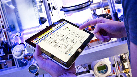  (öffnet Vergrößerung des Bildes)Das Bild zeigt einen Studenten mit Tablet in der Modellfabrik des Fachbereichs Maschinenbau.