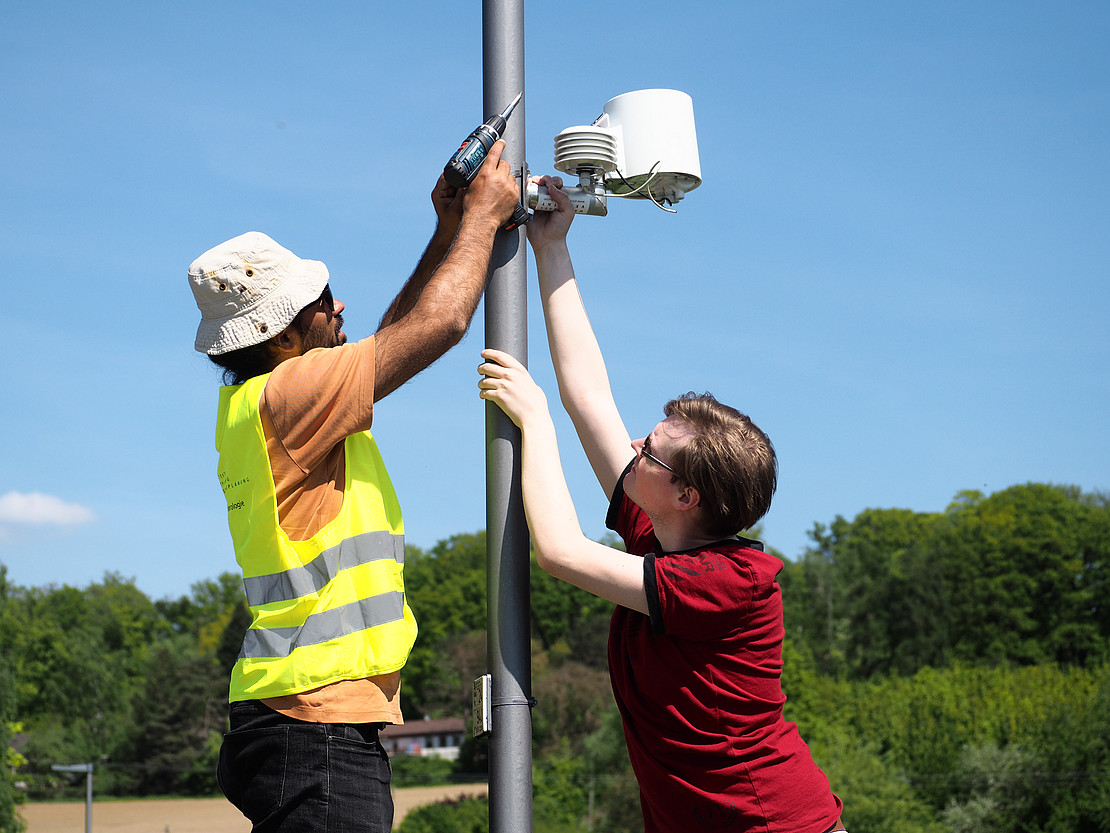 Two people install a device.