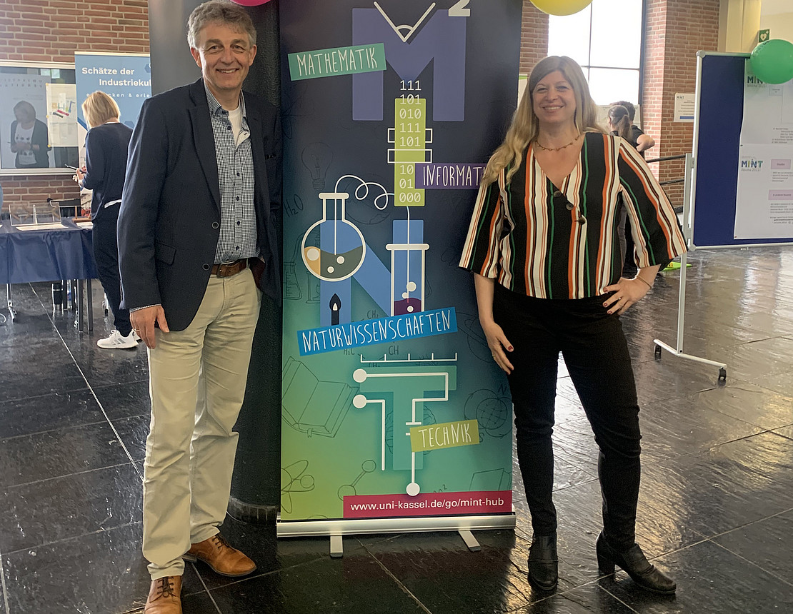Profs neben Plakat