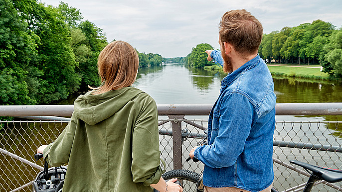Das Bild zeigt zwei junge Menschen mit ihren Fahrrädern auf der Drahtbrücke in Kassel
