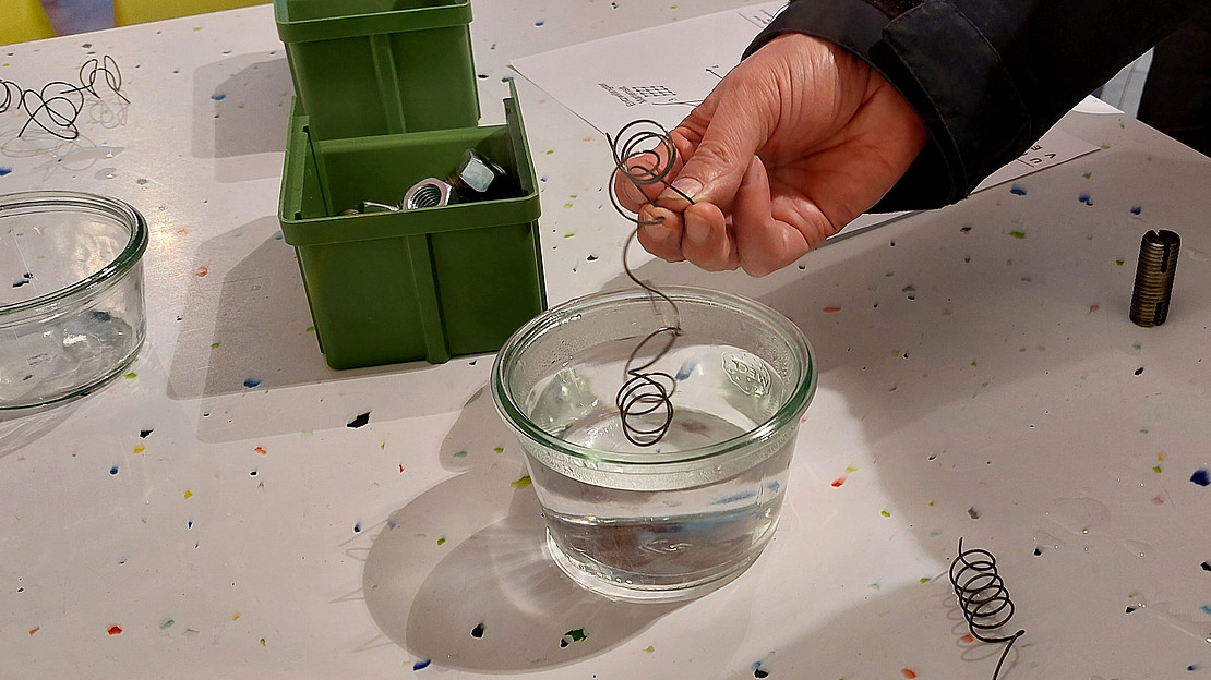 Hand dipping a wire into a glass of water