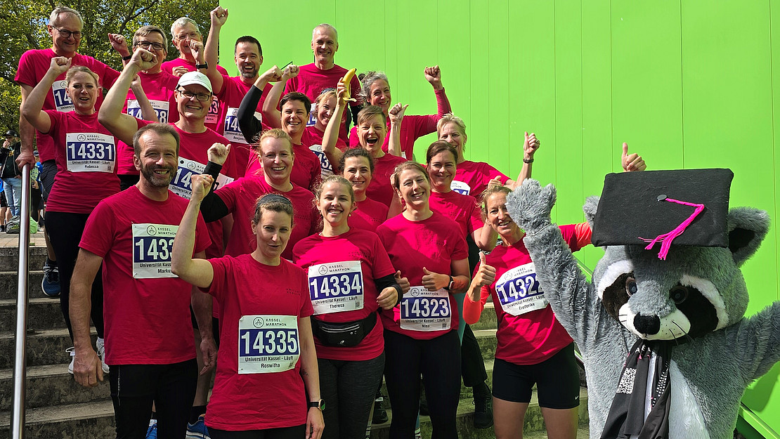 The photo shows the University of Kassel team running with mascot Kunibert. 