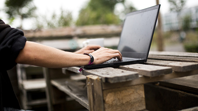 The picture shows hands writing on a laptop.